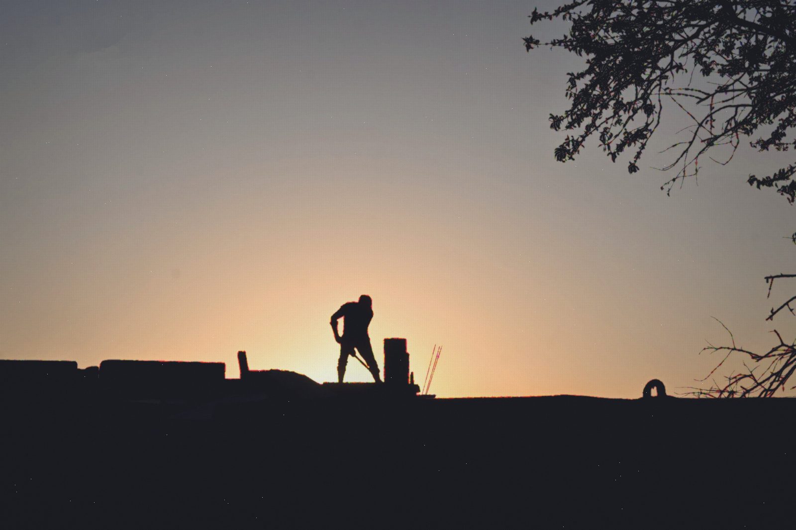 Construction worker silhouetted against a golden sunset on site