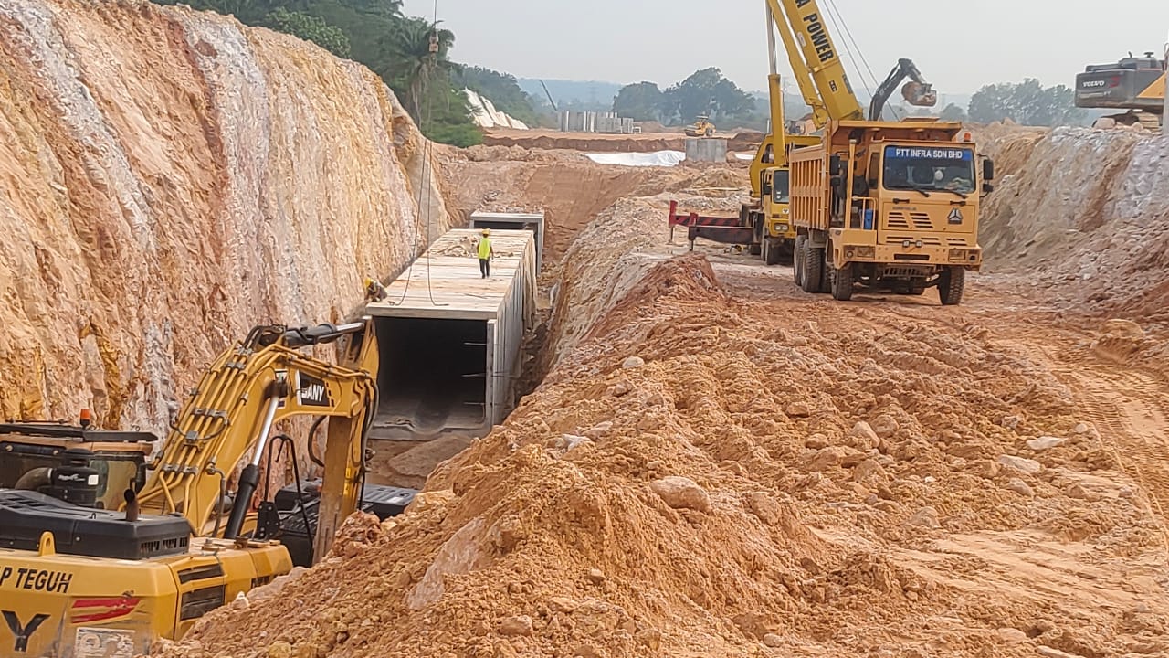 Precast concrete box culvert being laid in a deep excavation, with excavators and haulage working the cut